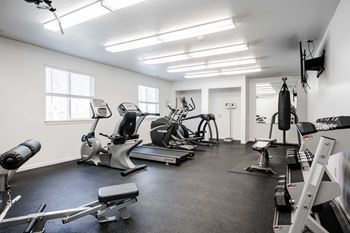 A spacious gym with a variety of equipment including treadmills, stationary bikes, and weight machines.